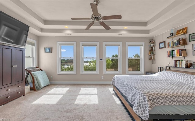 bedroom with light carpet, a ceiling fan, a tray ceiling, and recessed lighting