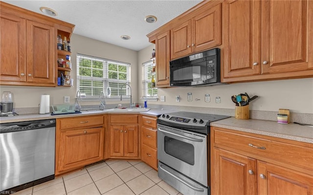kitchen with brown cabinetry, appliances with stainless steel finishes, light countertops, a sink, and light tile patterned flooring