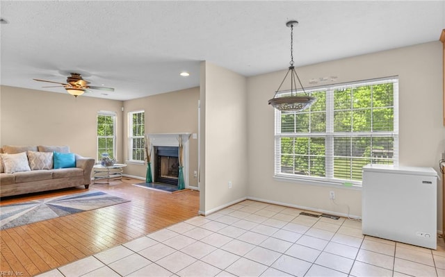 living area with light tile patterned floors, a fireplace with raised hearth, baseboards, recessed lighting, and a ceiling fan