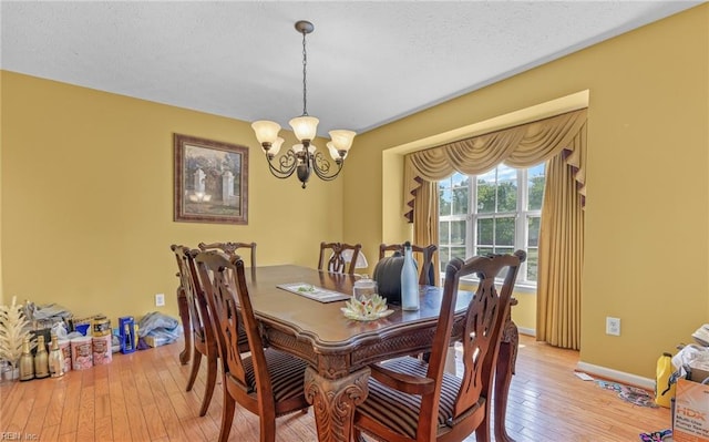 dining space featuring light wood finished floors, an inviting chandelier, and baseboards