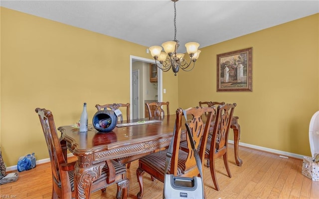 dining room with an inviting chandelier, light wood-style floors, and baseboards