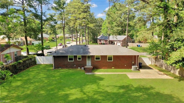 back of property with brick siding, a lawn, a shingled roof, and a fenced backyard