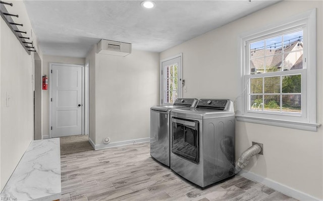 washroom with light wood-type flooring, baseboards, independent washer and dryer, and laundry area