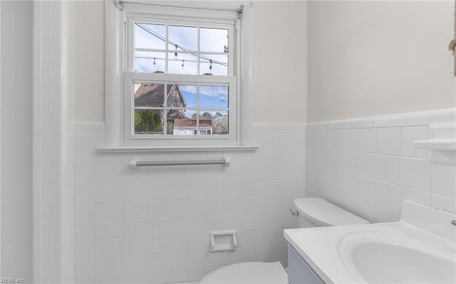 bathroom with tile walls, wainscoting, vanity, and toilet