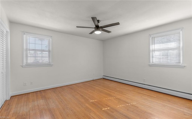 unfurnished room featuring baseboard heating, hardwood / wood-style flooring, a ceiling fan, and plenty of natural light