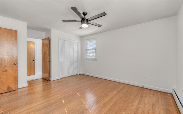 unfurnished bedroom featuring a baseboard heating unit, light wood finished floors, baseboards, and ceiling fan