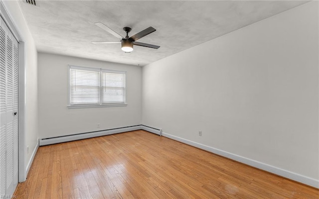 unfurnished bedroom with a closet, light wood finished floors, baseboards, and baseboard heating
