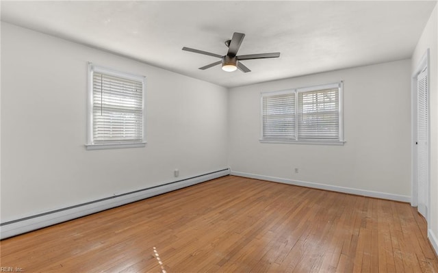 unfurnished bedroom with a baseboard heating unit, wood-type flooring, baseboards, and multiple windows