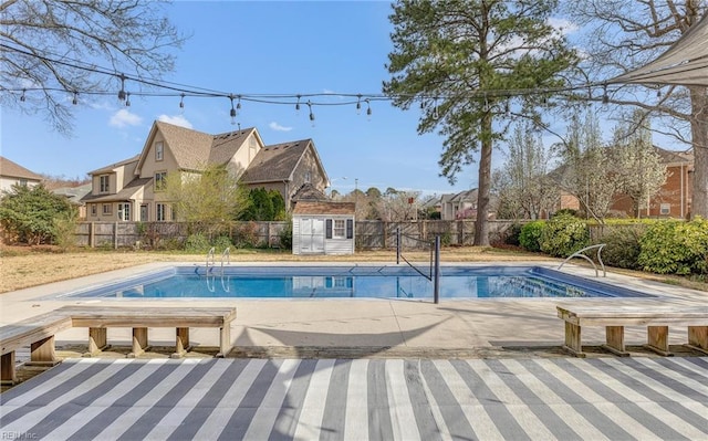 view of pool with a fenced backyard, an outbuilding, a patio area, and a storage unit
