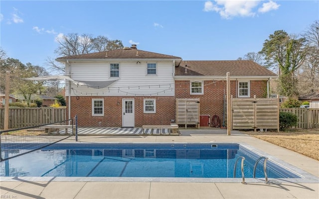 back of property with brick siding, fence, a patio area, and a fenced in pool