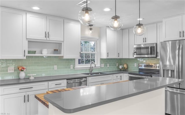 kitchen featuring white cabinets, dark countertops, stainless steel appliances, and a sink