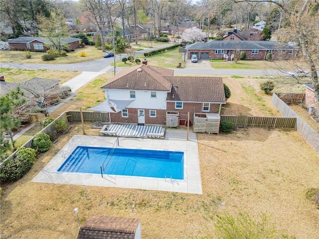 view of swimming pool featuring a lawn, a fenced backyard, a fenced in pool, and a residential view