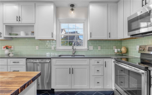 kitchen with white cabinets, wooden counters, open shelves, a sink, and appliances with stainless steel finishes