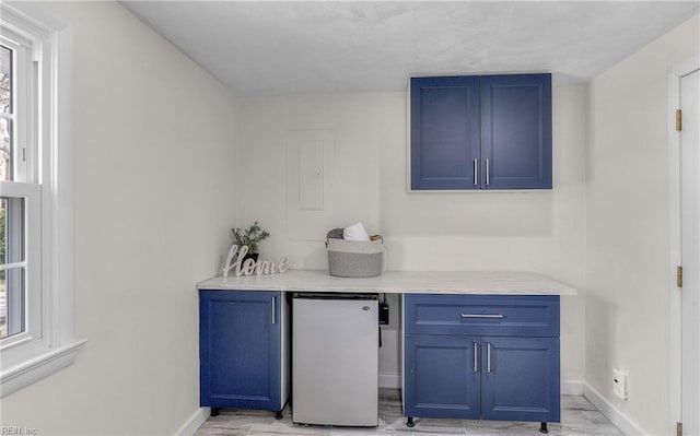 bar featuring freestanding refrigerator, light wood-style floors, and baseboards