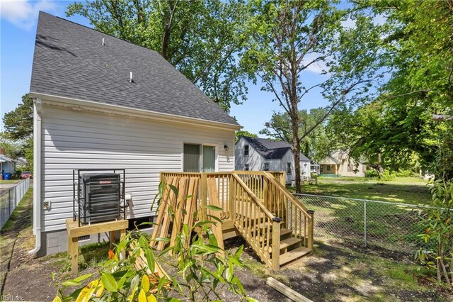 rear view of house featuring fence, a shingled roof, and a deck