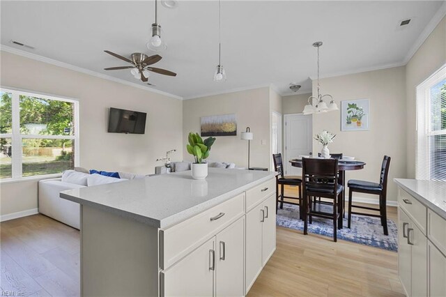 kitchen featuring ornamental molding, light wood-style floors, and ceiling fan with notable chandelier