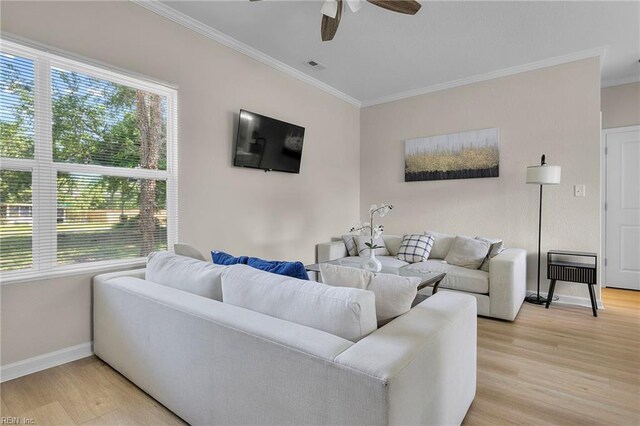 living area featuring light wood finished floors, ceiling fan, baseboards, and ornamental molding