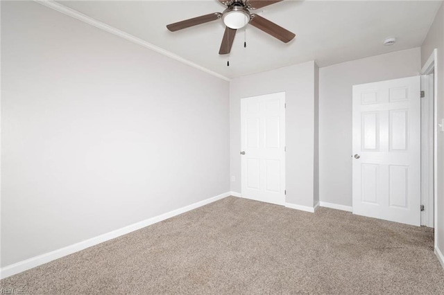 unfurnished bedroom with a ceiling fan, carpet flooring, crown molding, and baseboards