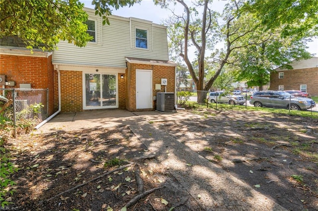 rear view of property with fence, central AC unit, and brick siding