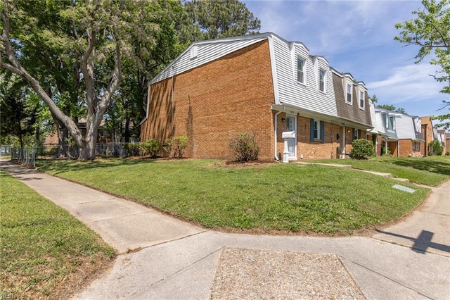 view of side of home featuring fence, a yard, and brick siding