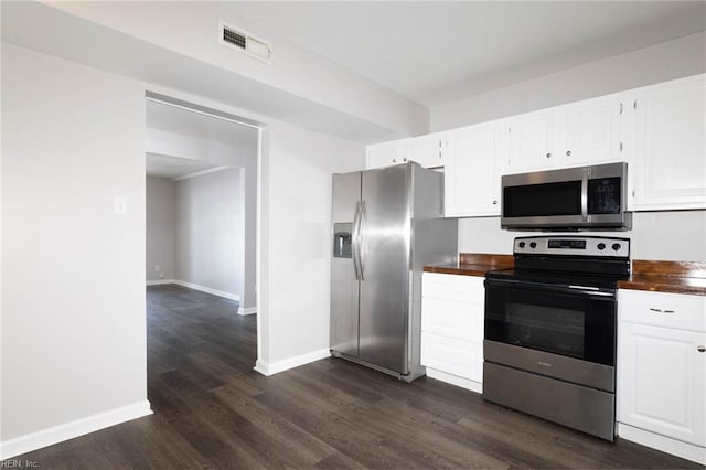 kitchen with white cabinets, visible vents, stainless steel appliances, baseboards, and dark wood finished floors