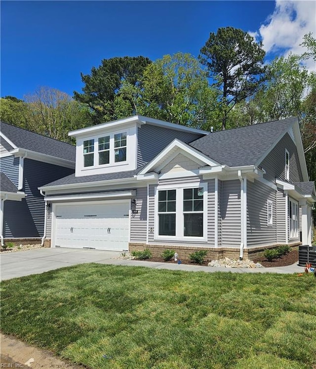 view of front of house featuring an attached garage, driveway, a front yard, and central AC unit
