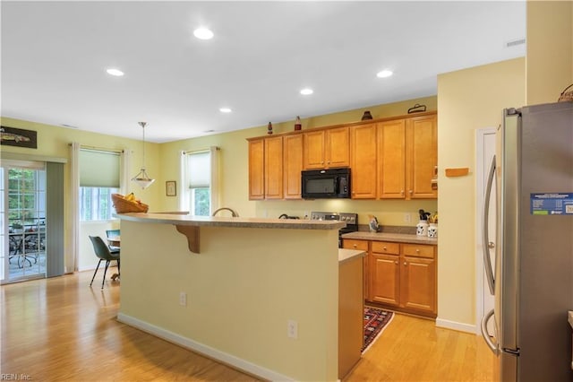 kitchen featuring appliances with stainless steel finishes, light countertops, light wood finished floors, and a healthy amount of sunlight