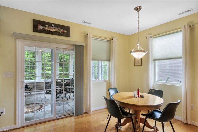 dining area with light wood-type flooring, visible vents, and baseboards