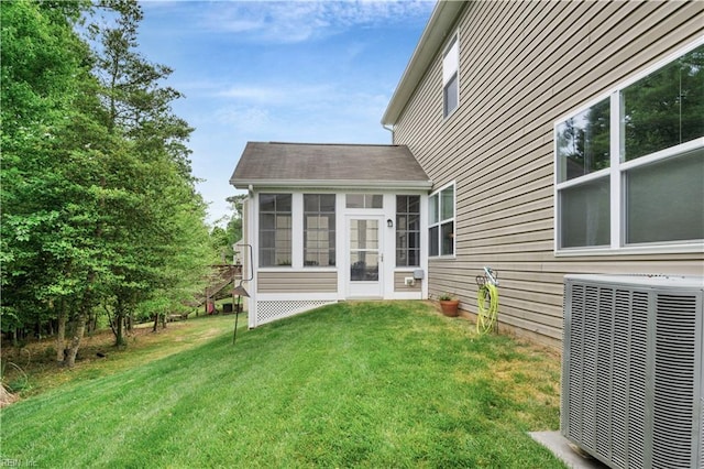 rear view of house with central AC, a sunroom, and a yard