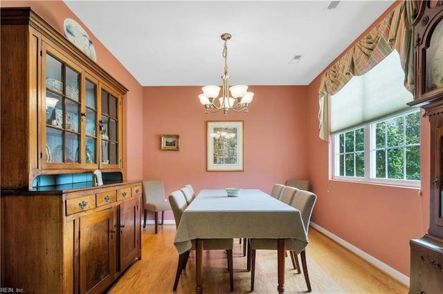 dining room with a chandelier, light wood-style floors, visible vents, and baseboards