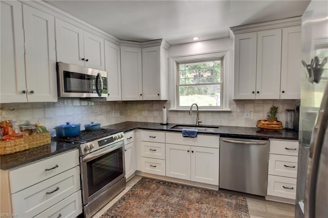 kitchen with recessed lighting, a sink, stainless steel appliances, decorative backsplash, and dark stone countertops