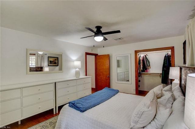 bedroom featuring a closet, a ceiling fan, a walk in closet, visible vents, and dark wood finished floors