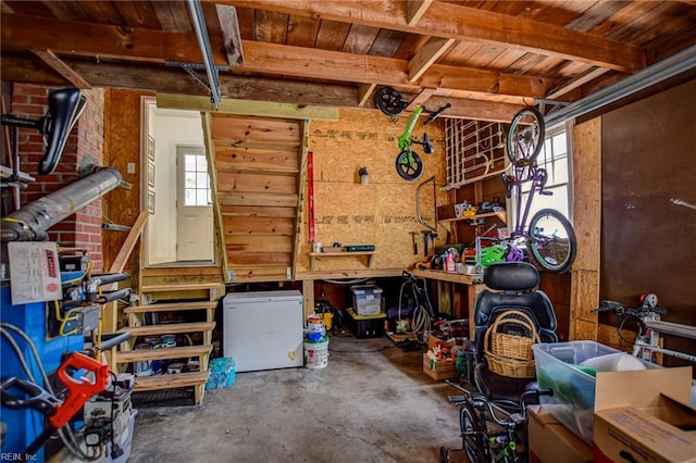 garage with a workshop area, wooden ceiling, wood walls, and fridge