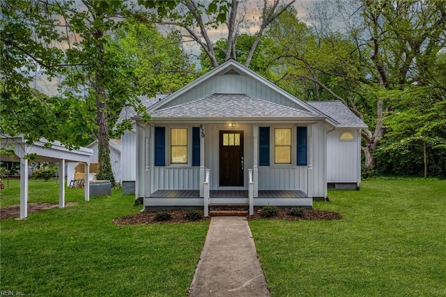 bungalow featuring a porch, board and batten siding, a front yard, and roof with shingles