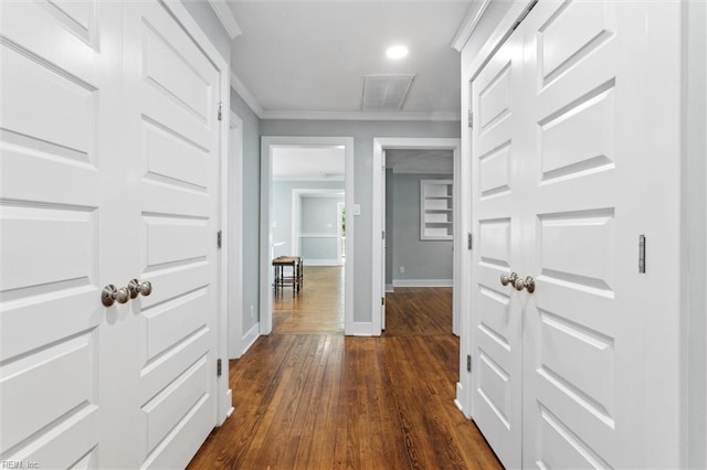 corridor featuring dark wood finished floors, recessed lighting, baseboards, visible vents, and crown molding