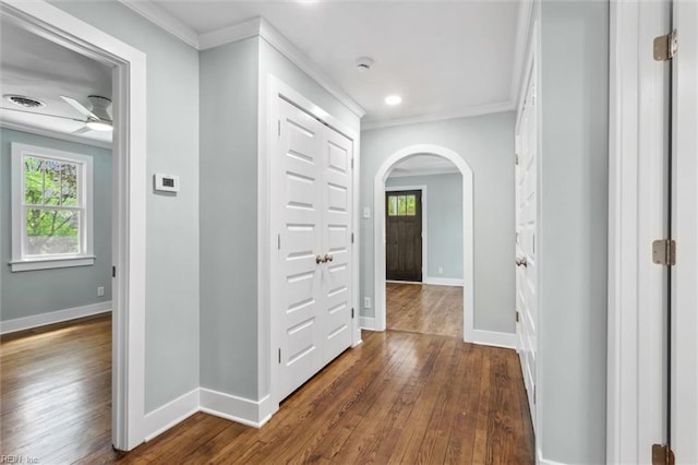 hallway with baseboards, arched walkways, dark wood-style flooring, and crown molding