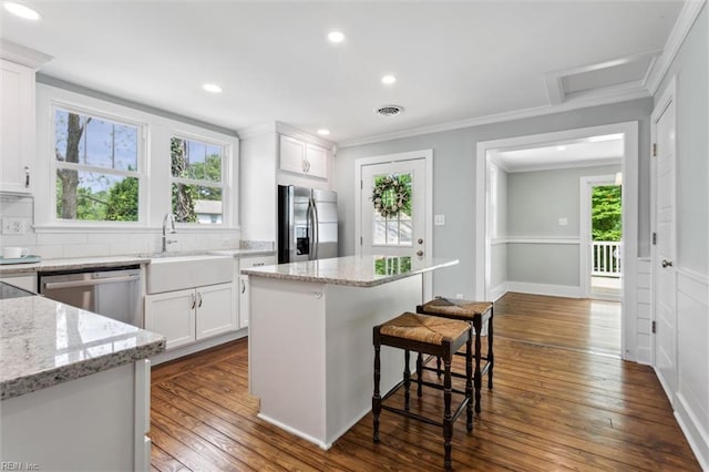 kitchen featuring a healthy amount of sunlight, stainless steel appliances, and ornamental molding