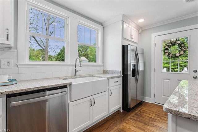 kitchen with appliances with stainless steel finishes, a healthy amount of sunlight, white cabinetry, and a sink