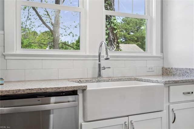 kitchen featuring white cabinetry, tasteful backsplash, stainless steel dishwasher, and a sink