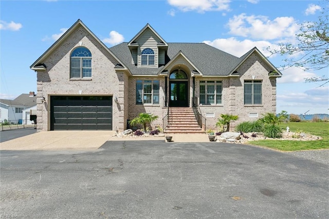 view of front of property with roof with shingles, an attached garage, driveway, and brick siding