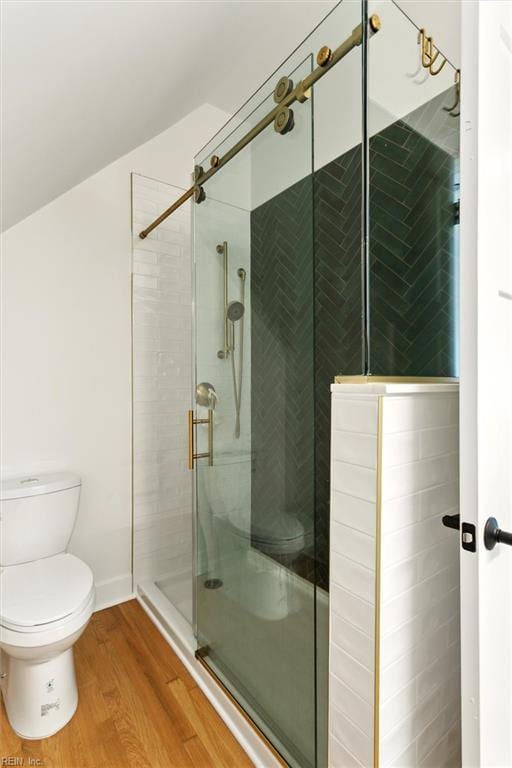 bathroom featuring toilet, wood finished floors, and a stall shower