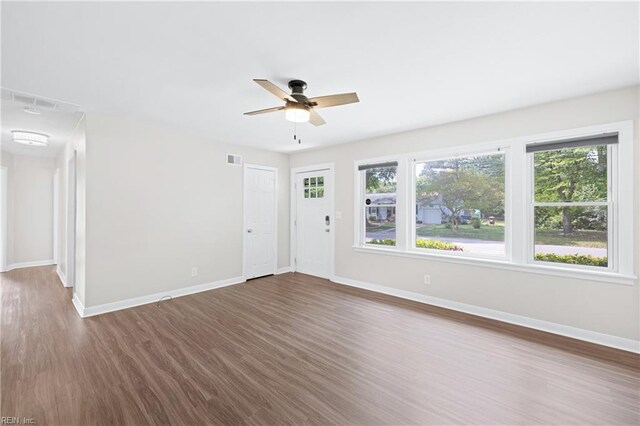 unfurnished living room with baseboards, a ceiling fan, wood finished floors, and a wealth of natural light