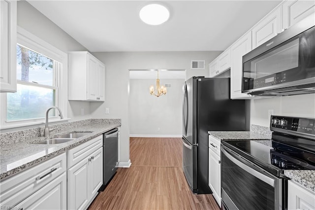 kitchen with stainless steel appliances, a sink, visible vents, a notable chandelier, and wood finished floors
