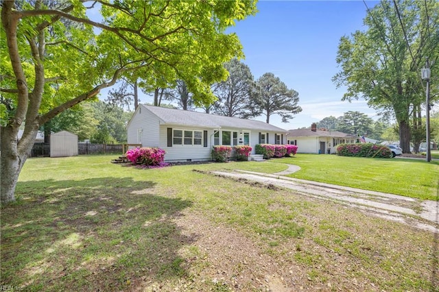 ranch-style house with a storage shed, a front yard, fence, and an outdoor structure