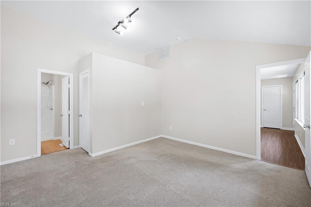 interior space featuring carpet floors, vaulted ceiling, visible vents, and baseboards