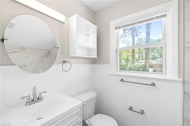 bathroom with wainscoting, visible vents, vanity, and toilet