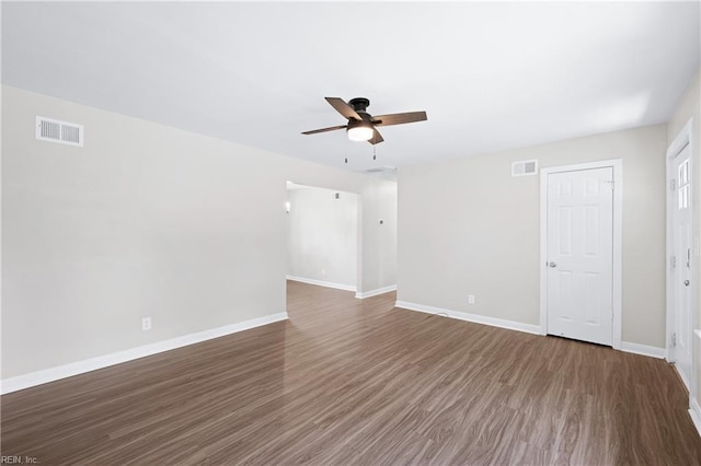 empty room with wood finished floors, visible vents, a ceiling fan, and baseboards