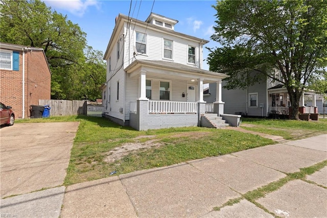 traditional style home featuring a front lawn, covered porch, and fence