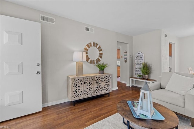 living area with wood finished floors, visible vents, and baseboards