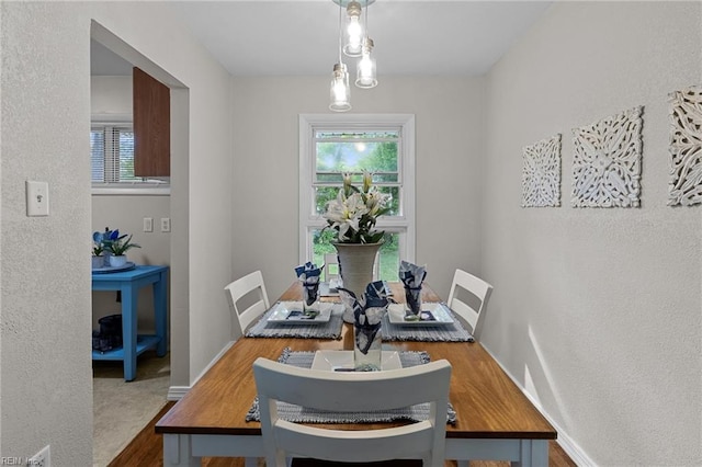 dining space featuring a textured wall, wood finished floors, and baseboards